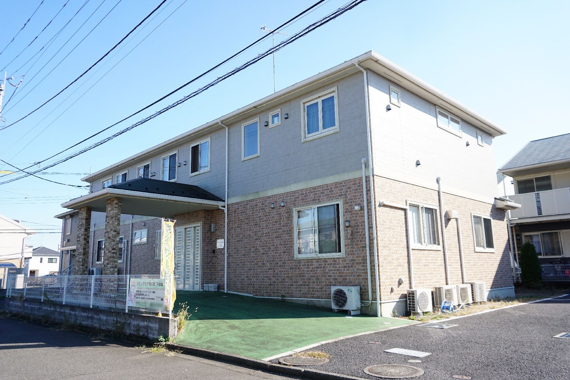 白と茶色の外壁でマンションのようにも見える施設の外観