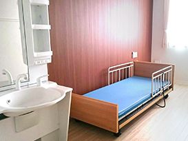介護ベッドが置かれたフローリングの部屋には大きな窓があり、車いす対応の洗面所があり、緊急通報装置が付いている。
