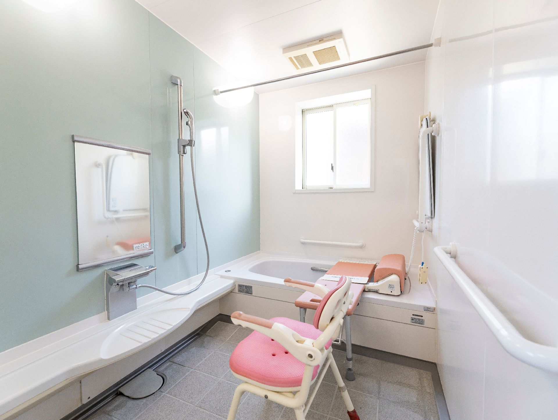 手すりが複数取り付けられ、シャワーチェアが置かれている浴室