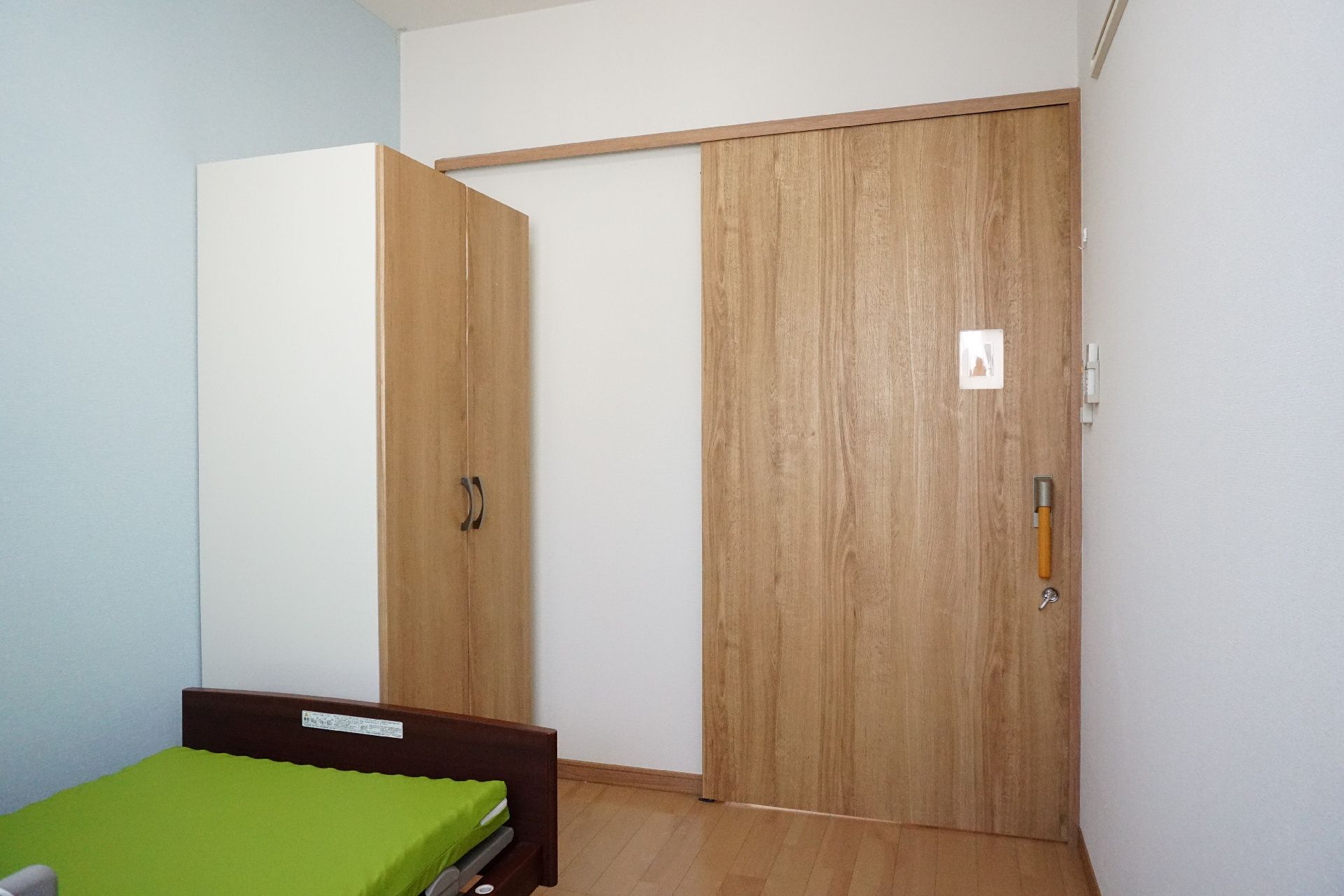 窓から日差しが入り、介護ベッドとエアコンが置かれている居室