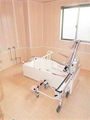 リフトが設置された広い浴室。手すり付きの浴槽が中央に置かれている。