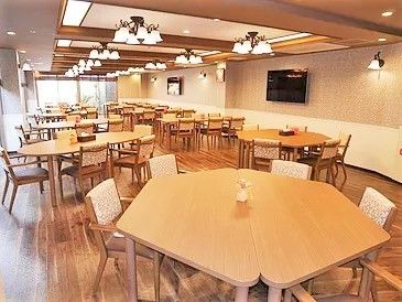 全入居者を収容可能な広い食堂。木製の大きなテーブルがたくさん並び、壁掛けテレビも2台ある。