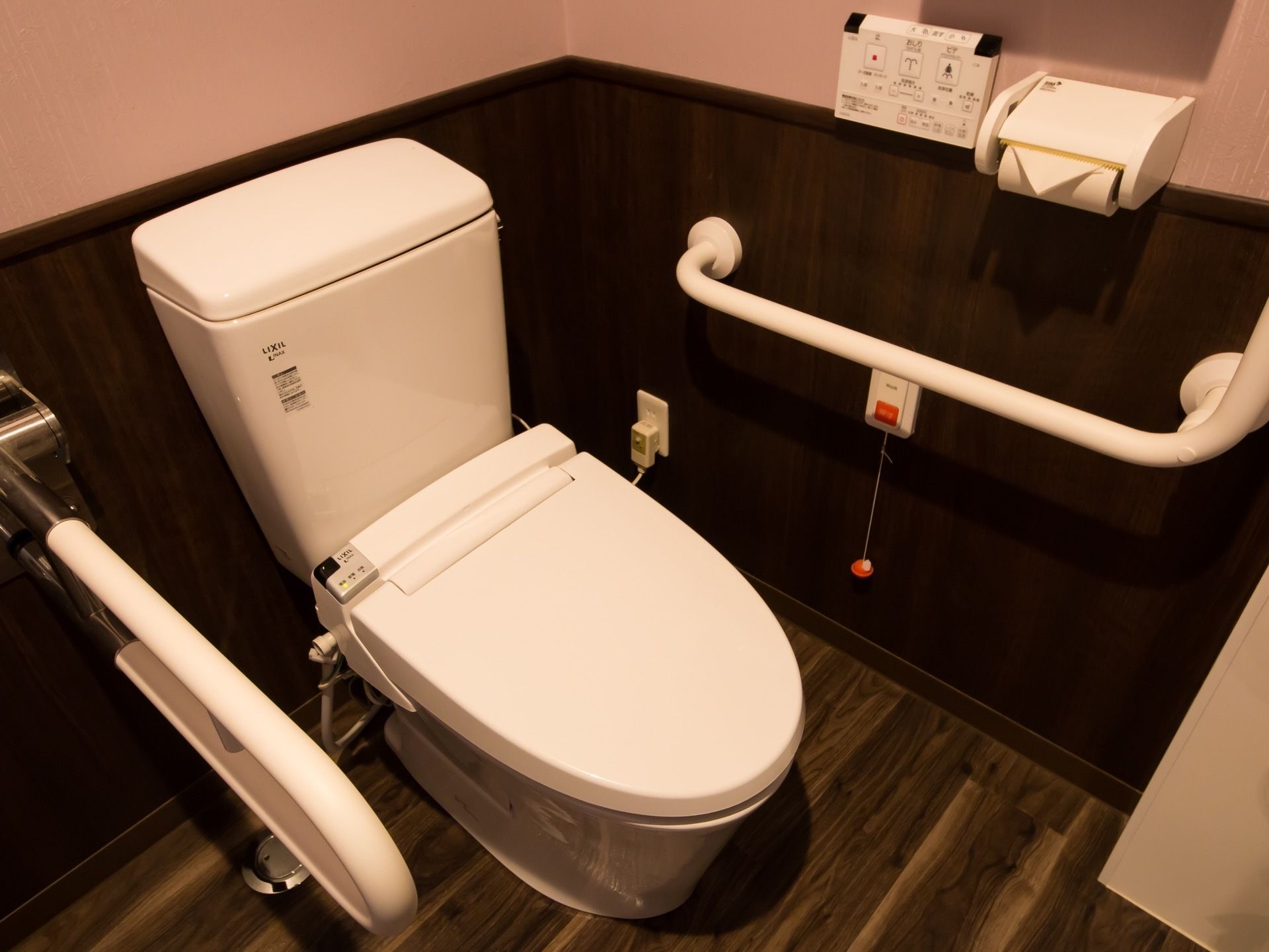 トイレの便器の手前側には可動式の手すりがある。入居者様は腰を掛けた後にその手すりを下げて使用することができる。