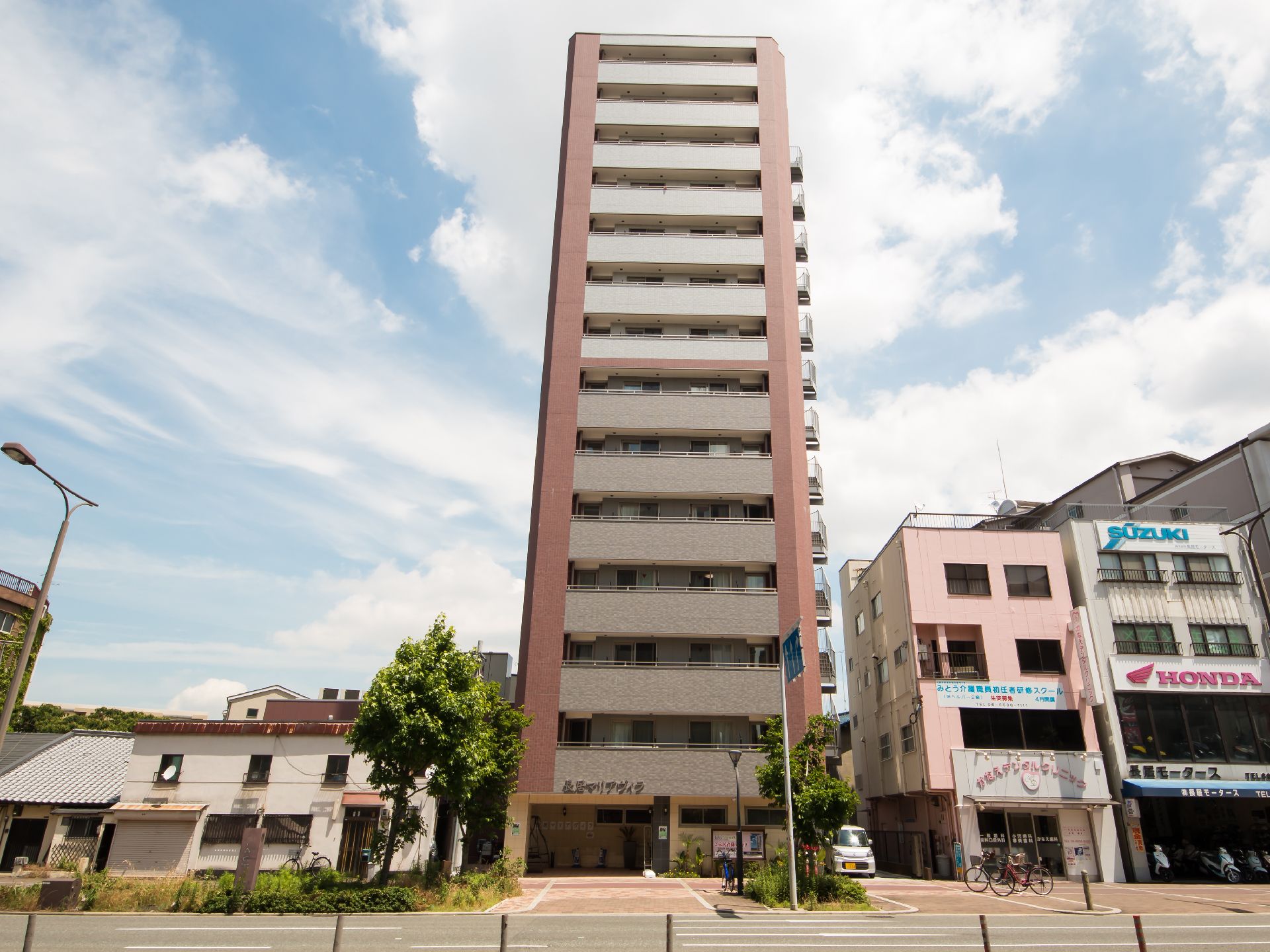 14階建ての大きな建物。白を基調としてブラウンのラインが入っている。