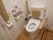 トイレには、茶色いひじ置きと背もたれを設置している。左側には、トイレットペーパー掛けも取りつけられている。