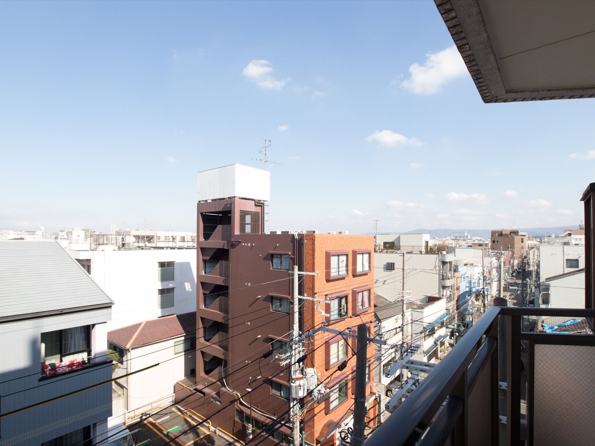 天気の良い日に撮影されたベランダから見た風景。周辺には住宅街が広がり、マンションが数多く建てられている。