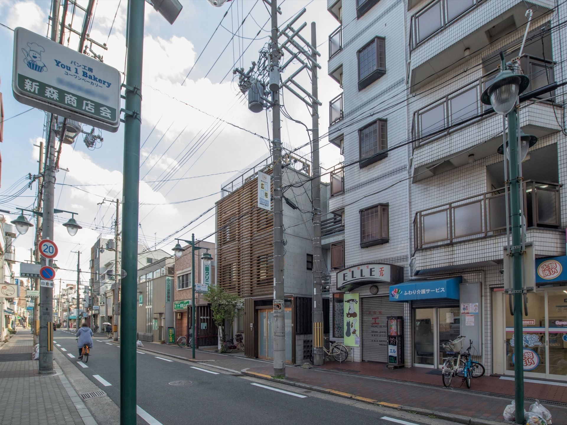 グループホーム周辺にクリニックがある。歩道には商店街のデザイン性のある街灯が設置されており、複数台の自転車が停められている。