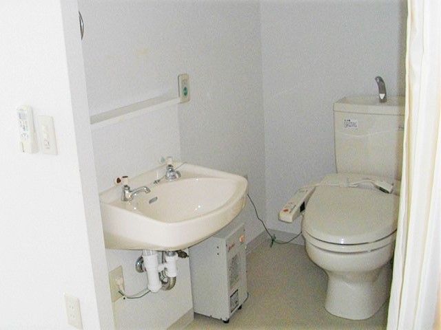 清潔感のあるデザインの水回りの写真。手前に洗面台があるタイプのトイレ