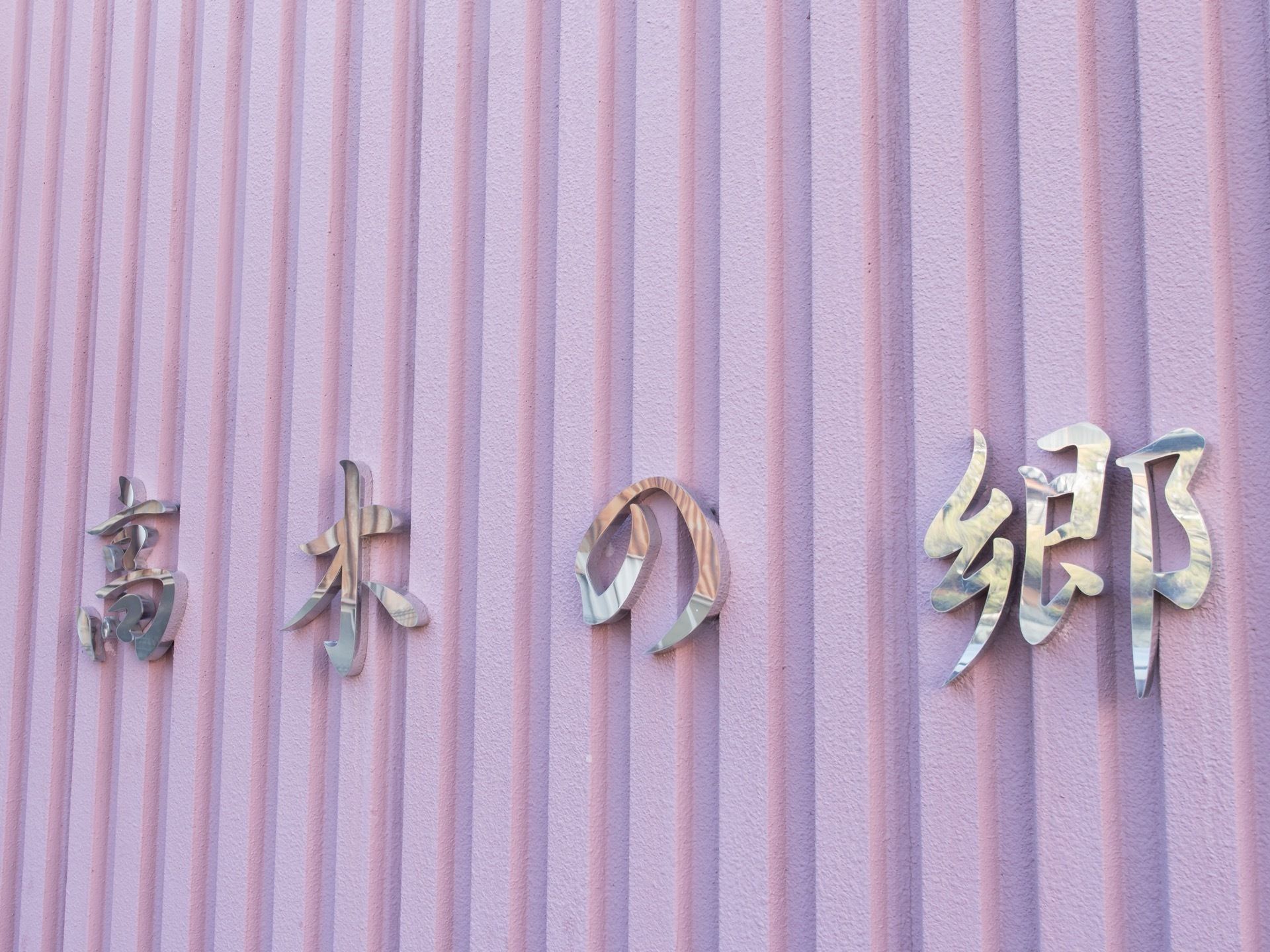 ラズベリー色のおしゃれな外壁である。壁には施設名が一文字ずつ取り付けられている。文字が大きいので遠くからでも見やすい。