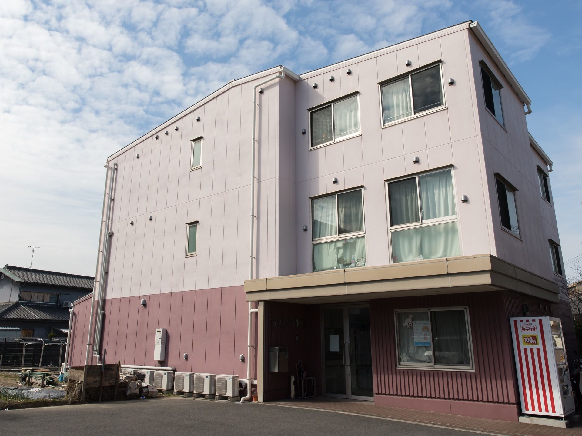 道路と施設の敷地の境は段差がない。建物の脇には自動販売機を設置している。施設は３階建てになっている。