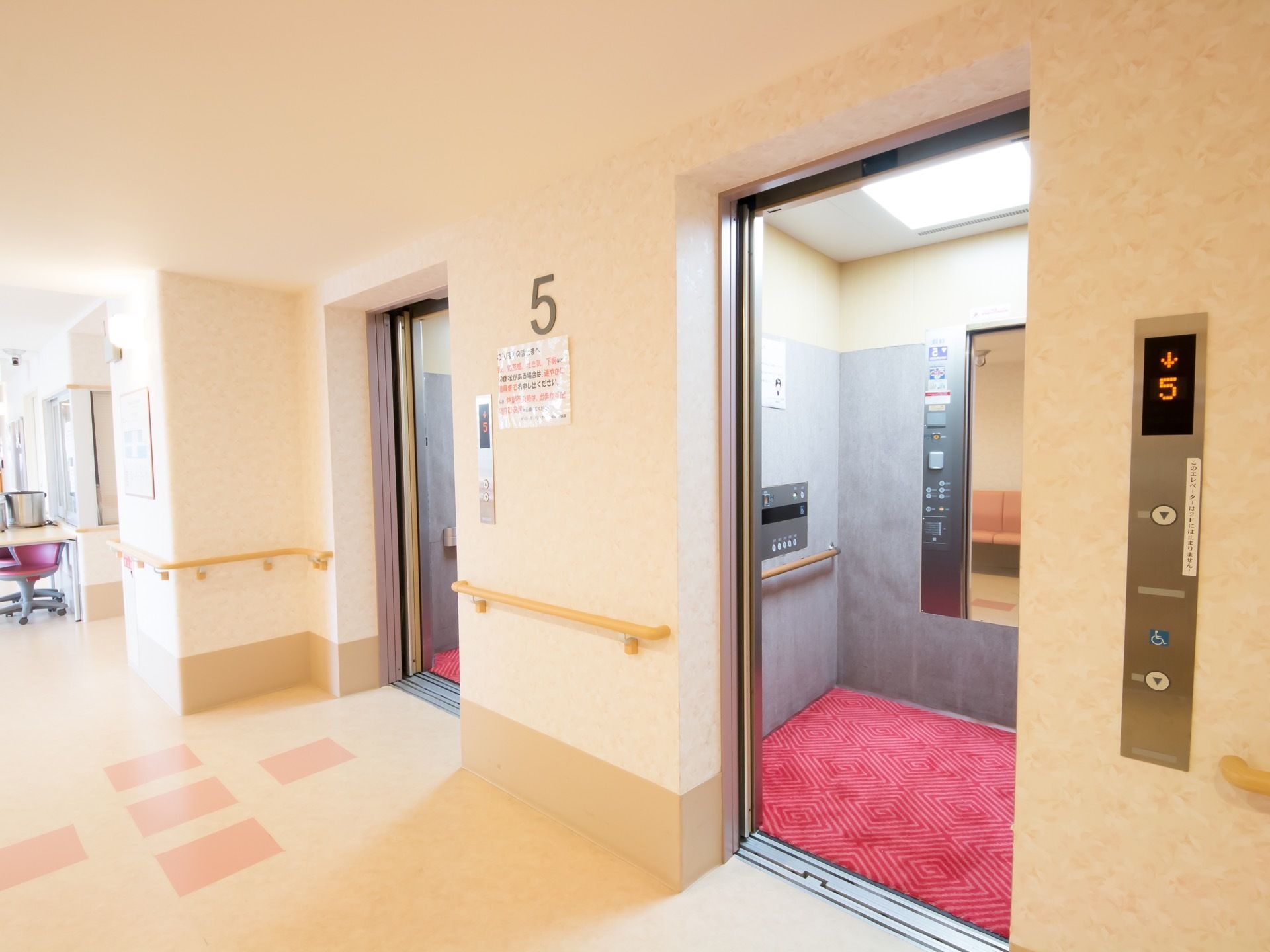 施設の廊下の一角には、エレベーター２つ設置されている。室内には赤いカーペットが敷かれ、鏡も取りつけられている。