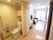 大きな窓から光が入る明るい部屋である。トイレのカーテンが開かれ、中の便器が見えている。天井にダウンライトとシーリングライトが設置されている。