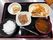 白いご飯にみそ汁そして野菜の小鉢や肉料理が並んだ黒いトレイには箸とスプーンが置かれている。