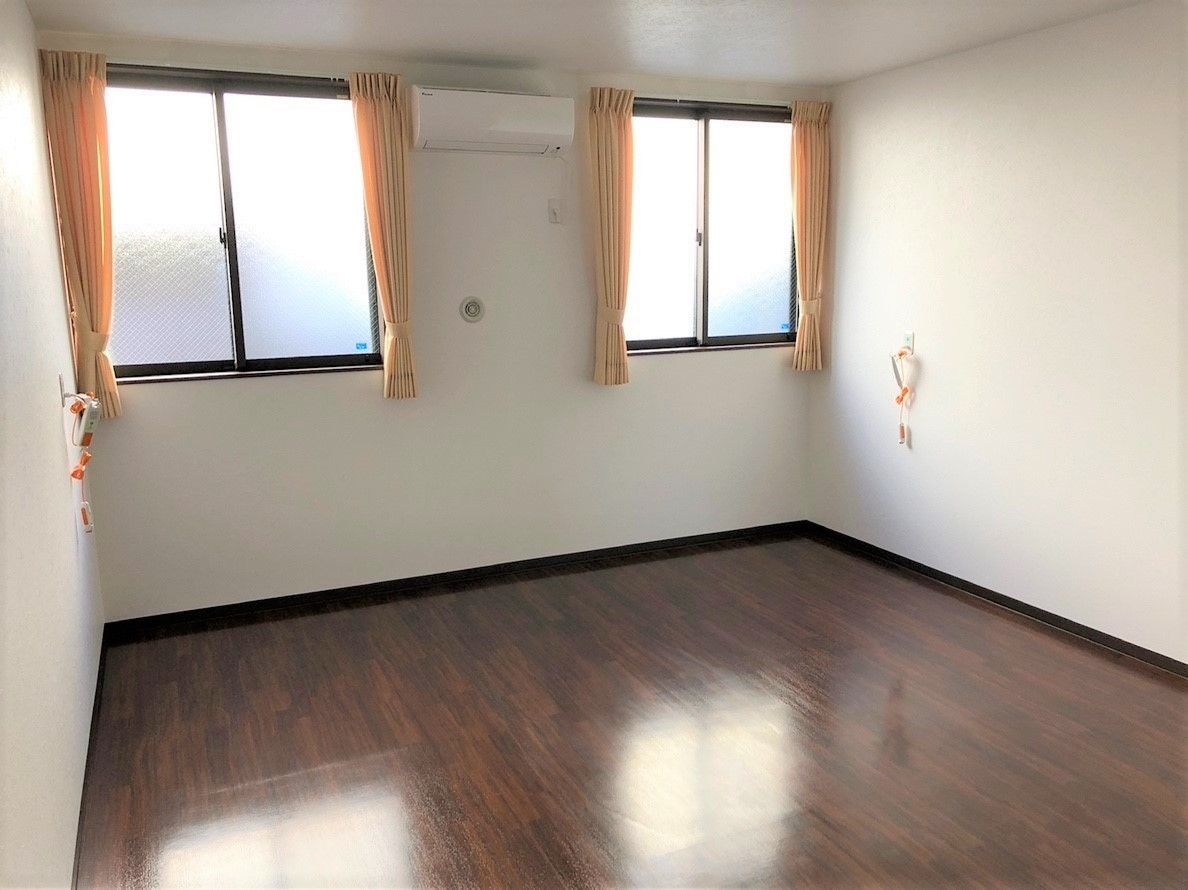 フローリングの居室。夫婦用の広さを確保した、窓やエアコン、収納があるシンプルな部屋。