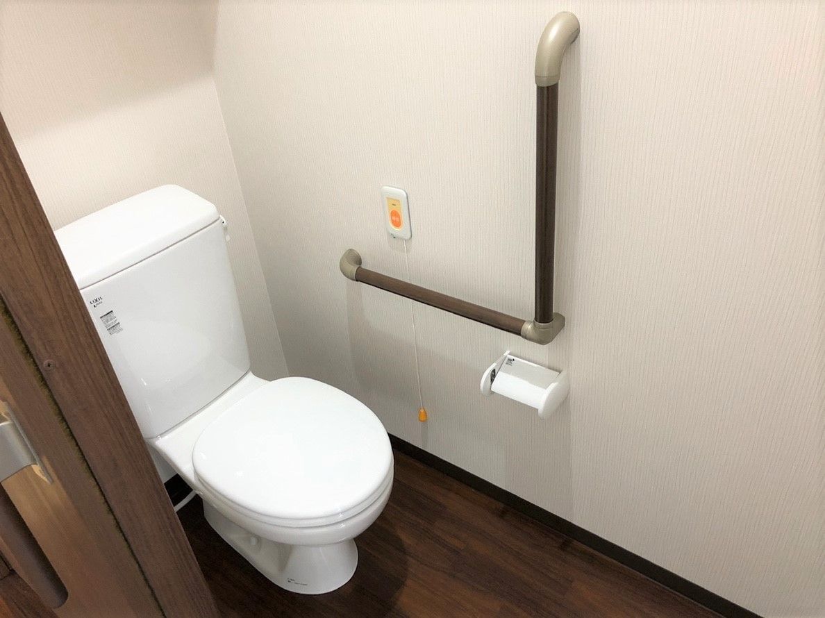 エル字型の手すりが壁に設置され、トイレのすぐ横に呼び出しボタンを設置。