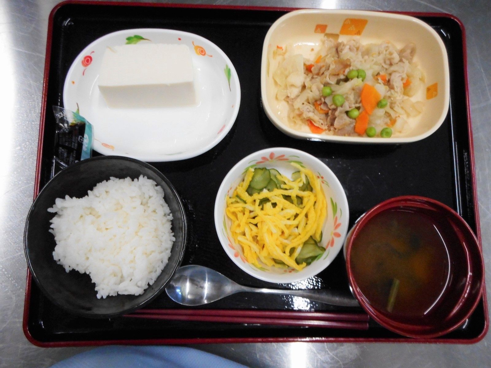 白いご飯とみそ汁、小鉢にメインが並んだ黒いお盆。