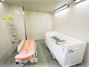 ピンクと白の機械浴槽が置かれた浴室にはシャワーも完備。体の状態に合わせて利用できる。