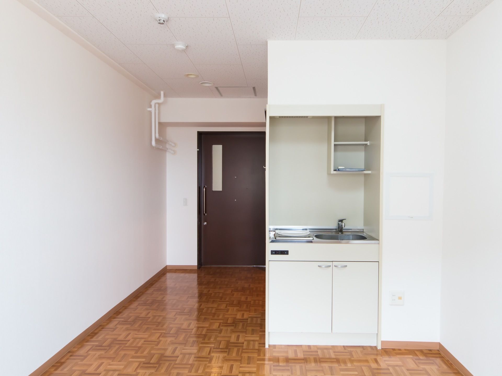 居室にはミニキッチンが設置されており、上には棚が取り付けられている。出入り口のドアには細長いガラスが付いている。