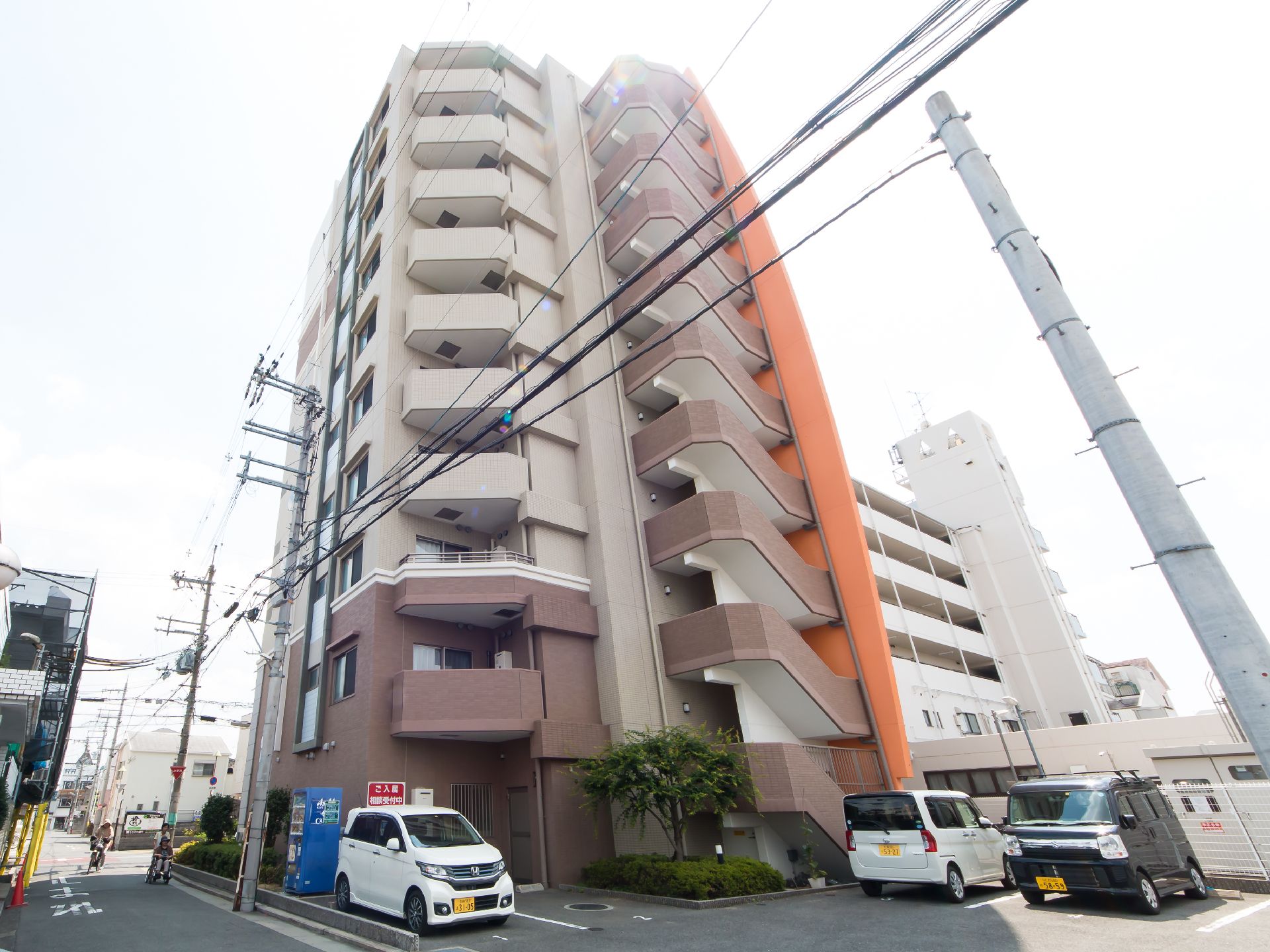ベージュとブラウンでまとめられた10階建ての建物。1階の中央部分に玄関がある。