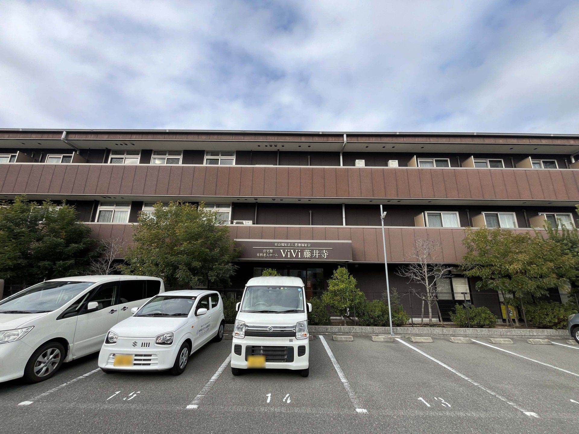 薬を飲む高齢女性に水を差し出す女性スタッフ