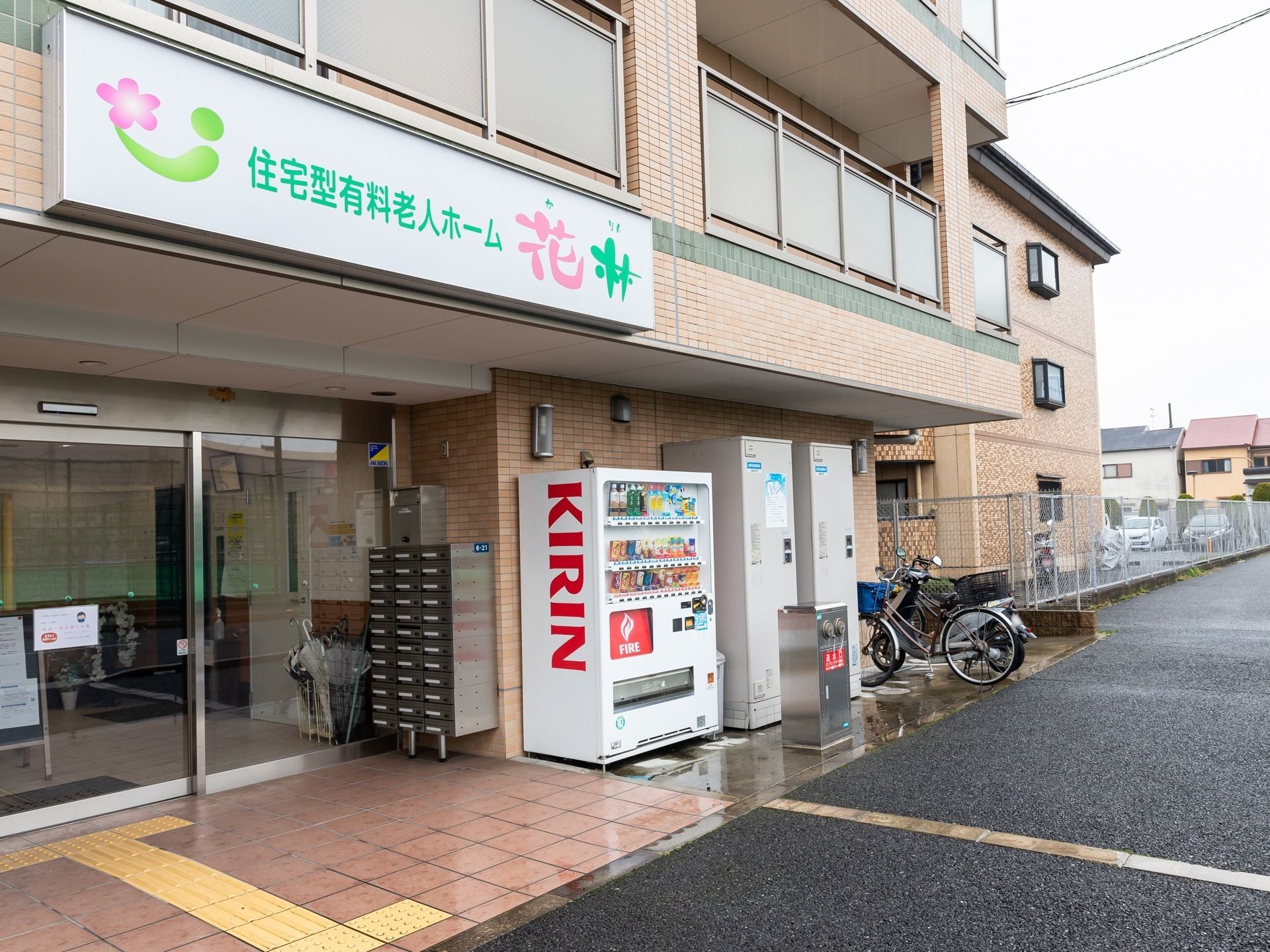 建物の正面部分には横長の看板が付いている。舗装された道の幅は広く、車を停めるスペースも確保されている。