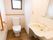 洗面台も設置された明るい洋式トイレがある。床はフローリングで、壁にはＬ字型の手すりがある。