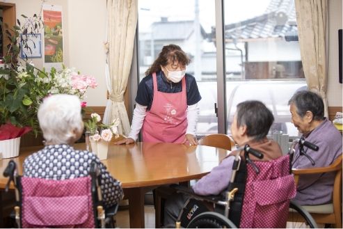 介護車両に移動する車椅子に乗った高齢女性と介助をする女性ヘルパー
