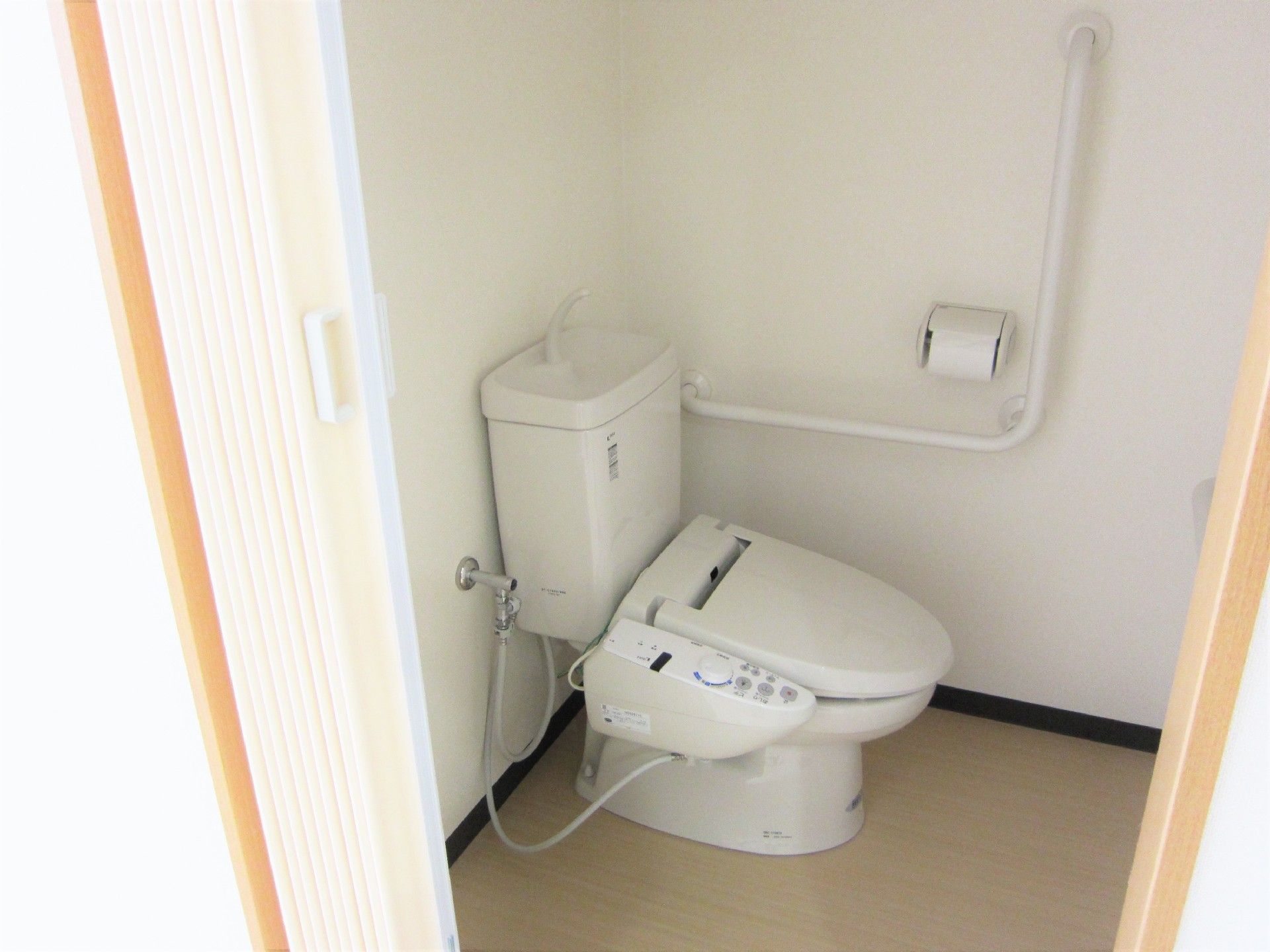 L字型の手すりが付いた高齢者用トイレの様子。ウォシュレットの設備もついている