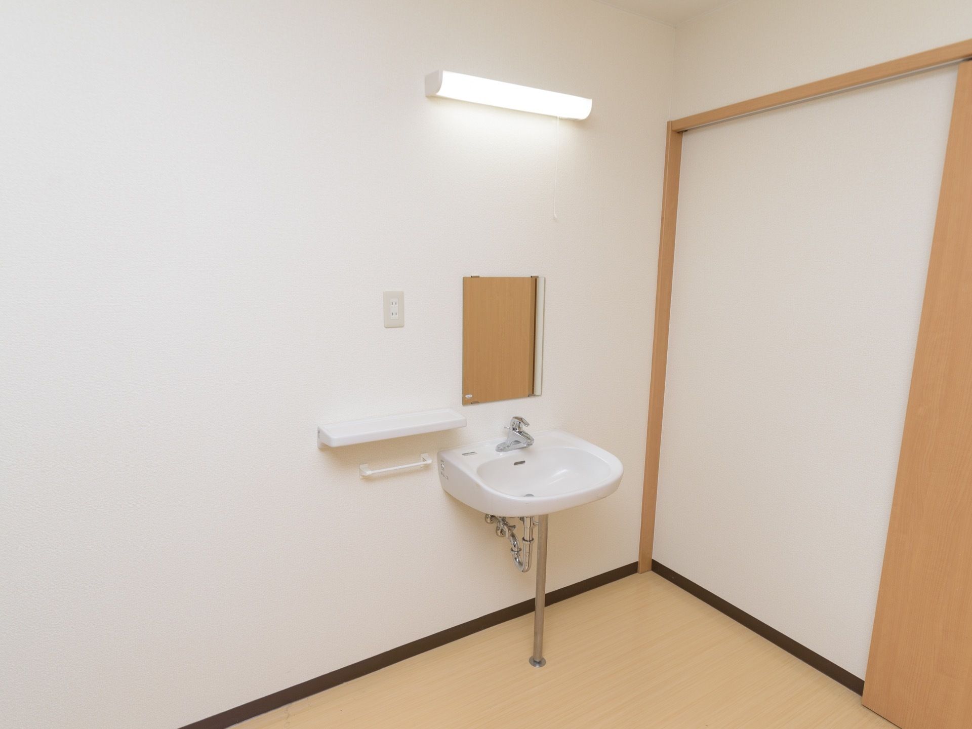ある一室に手洗い場が完備されている。鏡やライトが設置され、コンセントの下部に物を置くことのできるカウンターがある。