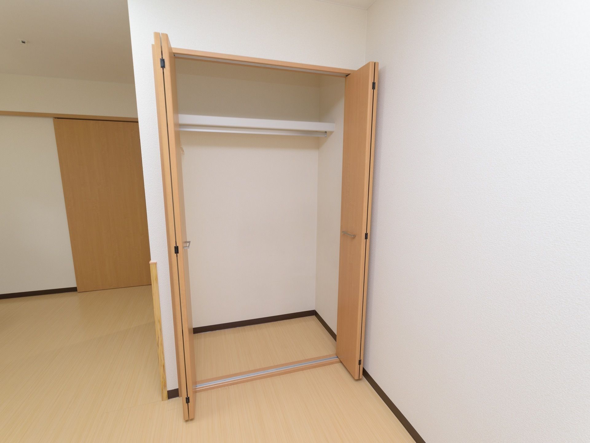 造り付けされている収納クローゼットである。やさしい配色の木目調で折りたたみ式、両開きの扉が設置されている。