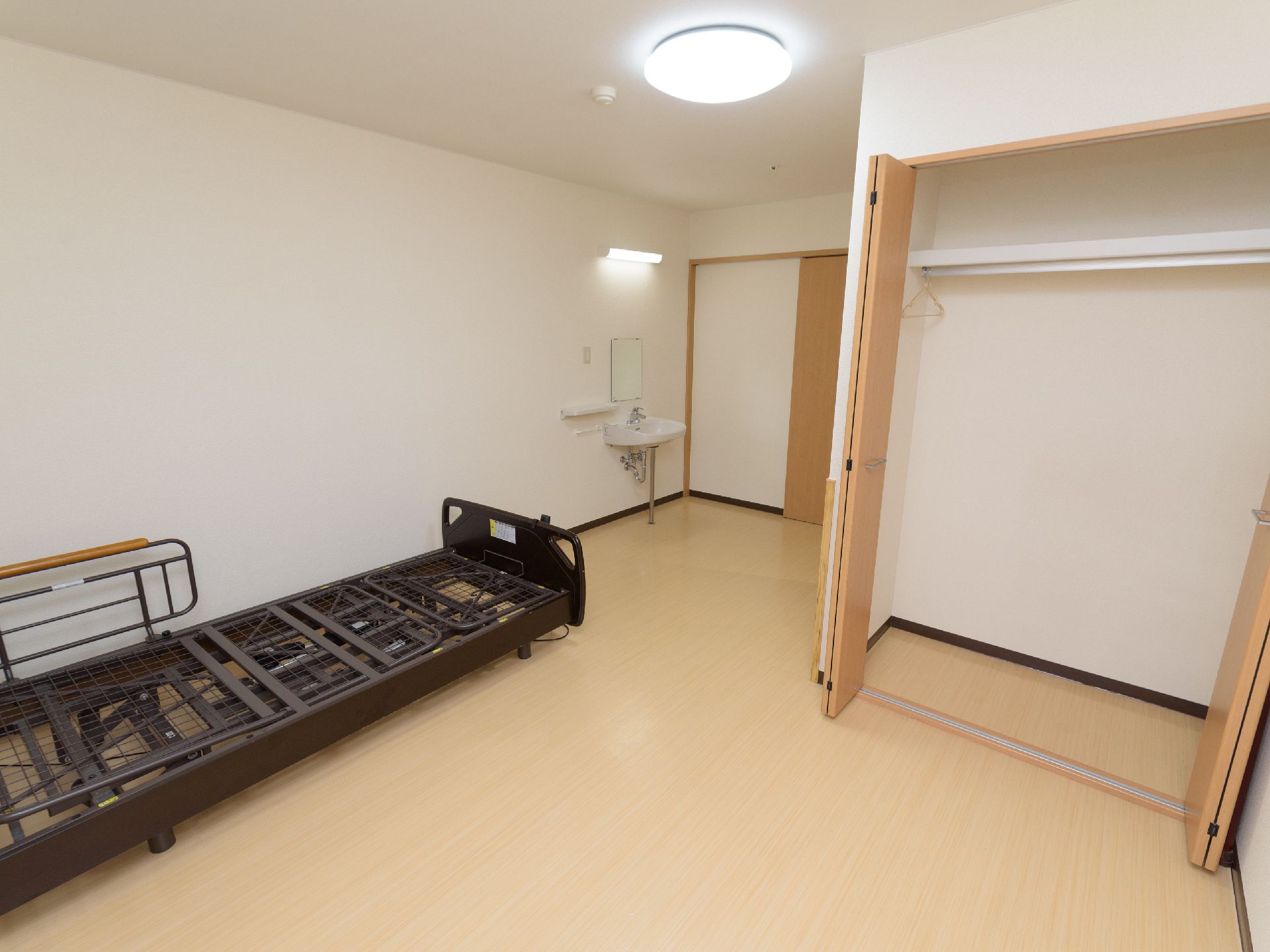 黒いベッドフレームが置かれており、洗面台があるお部屋