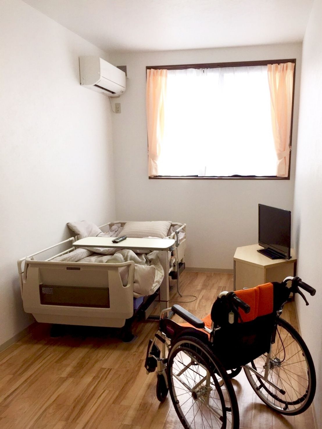 フローリングの部屋には車いすや介護用ベッド、テレビが置かれ、大きな窓が付いている。