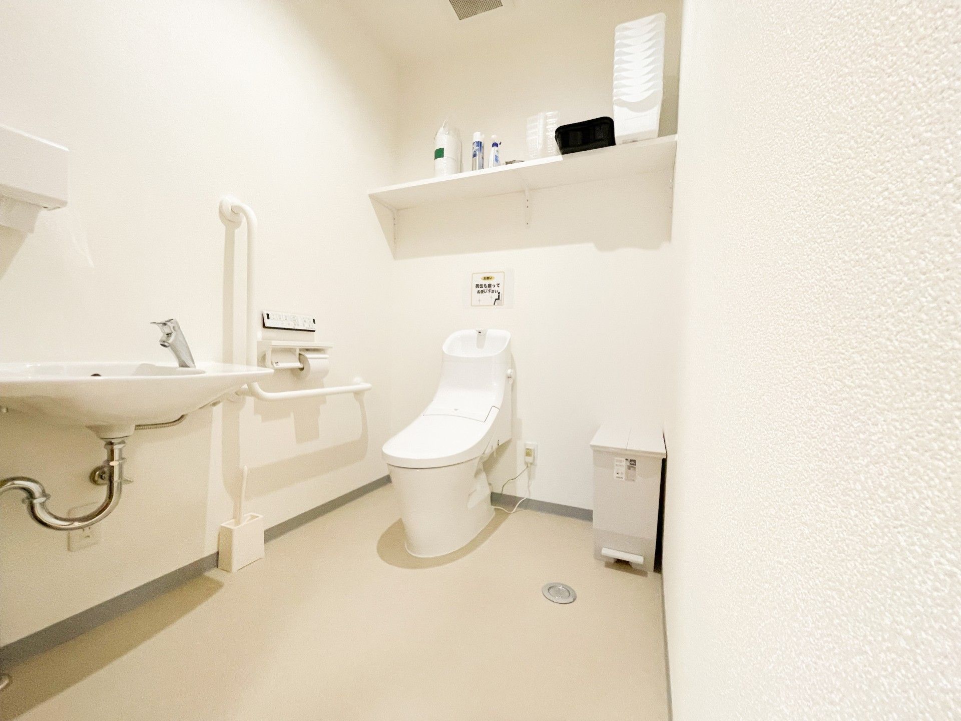 広いスペースが確保されたトイレである。温水洗浄便座が採用されており、操作ボタンが壁に取り付けられている。