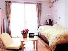 ベッドと一人用のソファが置いてある部屋の様子。ベランダにつながる窓がある