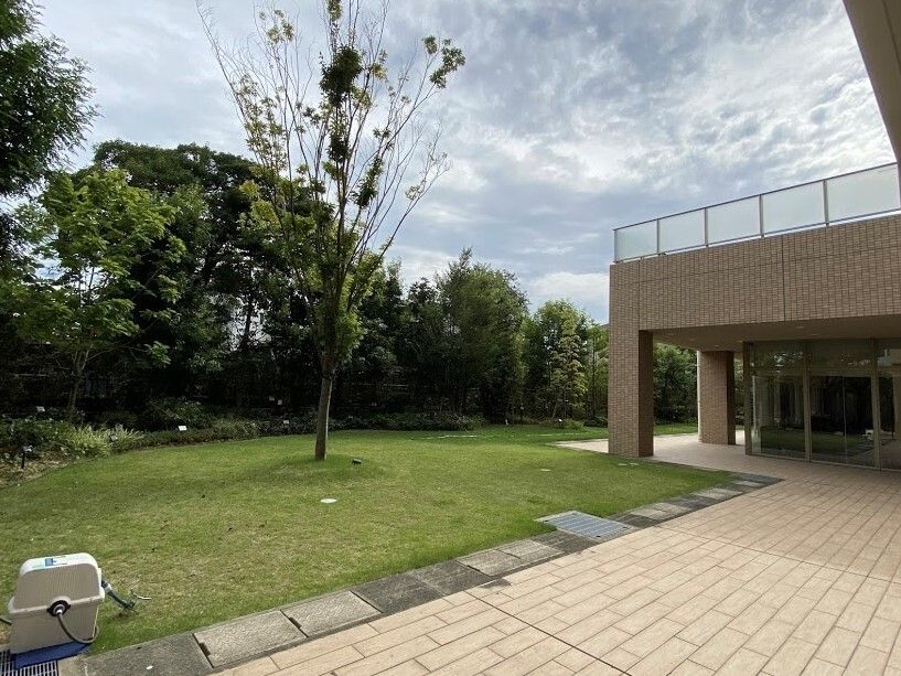 芝生と木がある庭と、ベージュ色のグループホームの一角