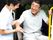 笑顔で福祉車両から降りようとしている眼鏡をかけた高齢男性とサポートしている若いスタッフ。