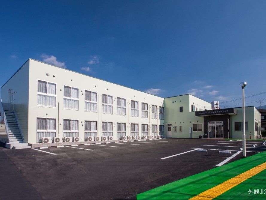 白い２階建ての建物は日当たり良好で敷地内には広い駐車場があり、外灯も設置されている。