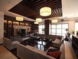 壁一面が窓となっていて明るいロビー。大型のテレビが置かれ囲むようにソファが置かれている。