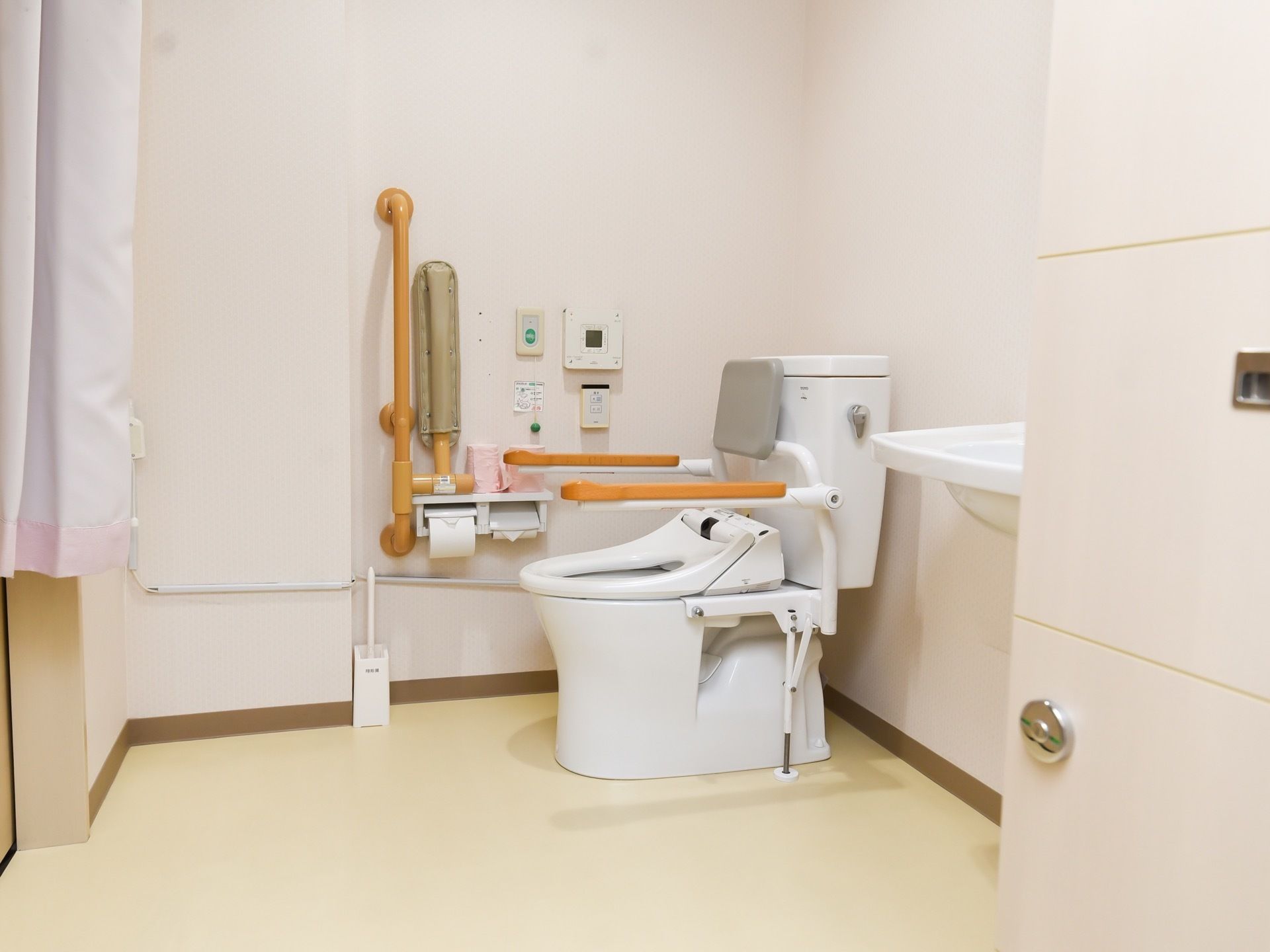 白色を基調とした、明るい雰囲気のトイレである。手すりが備えつけられているほか、背もたれクッションも設置されている。