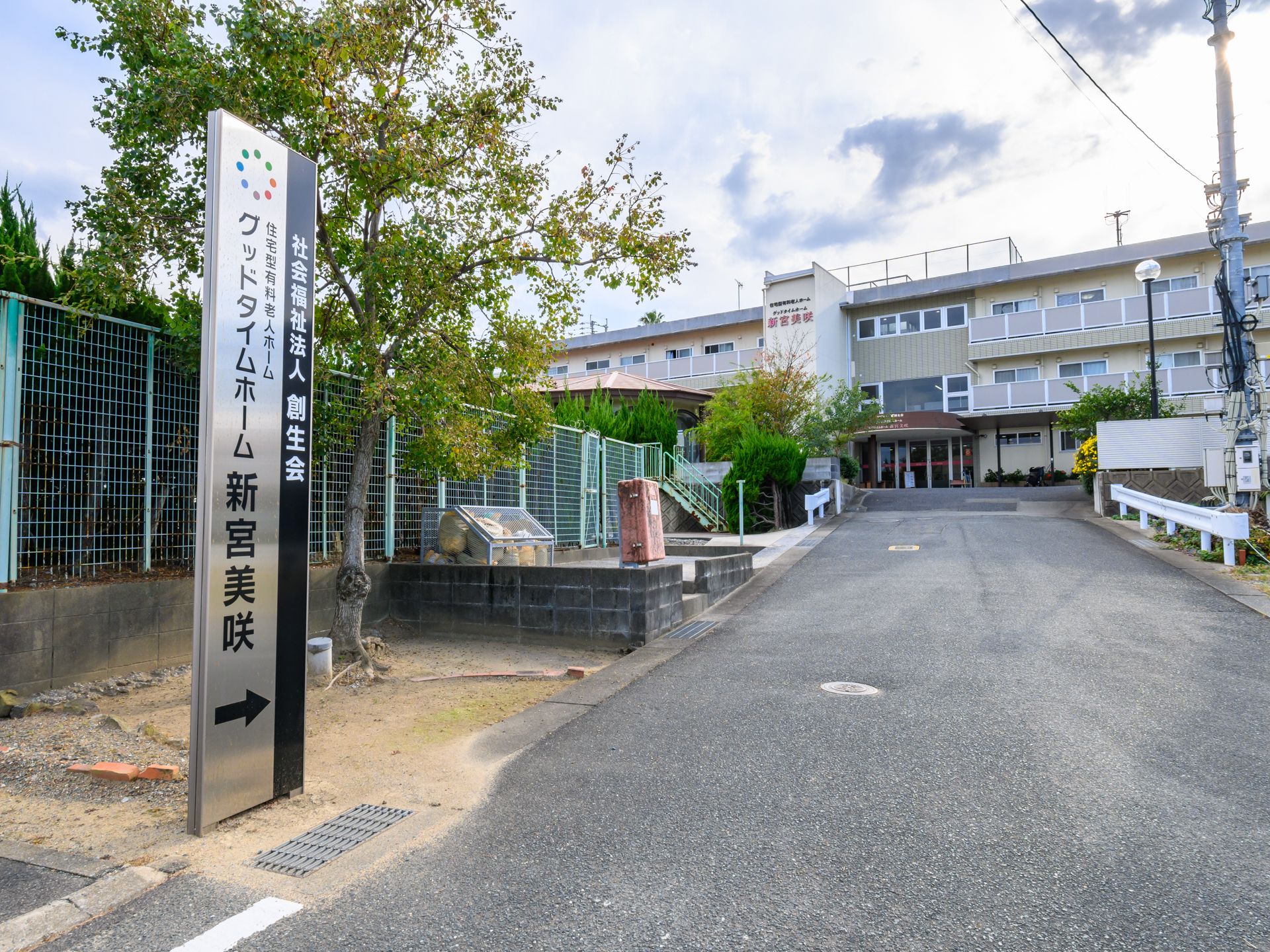 白いシャツを着た高齢女性とブルーのユニフォームを着た男性スタッフが笑顔で体操をしている。