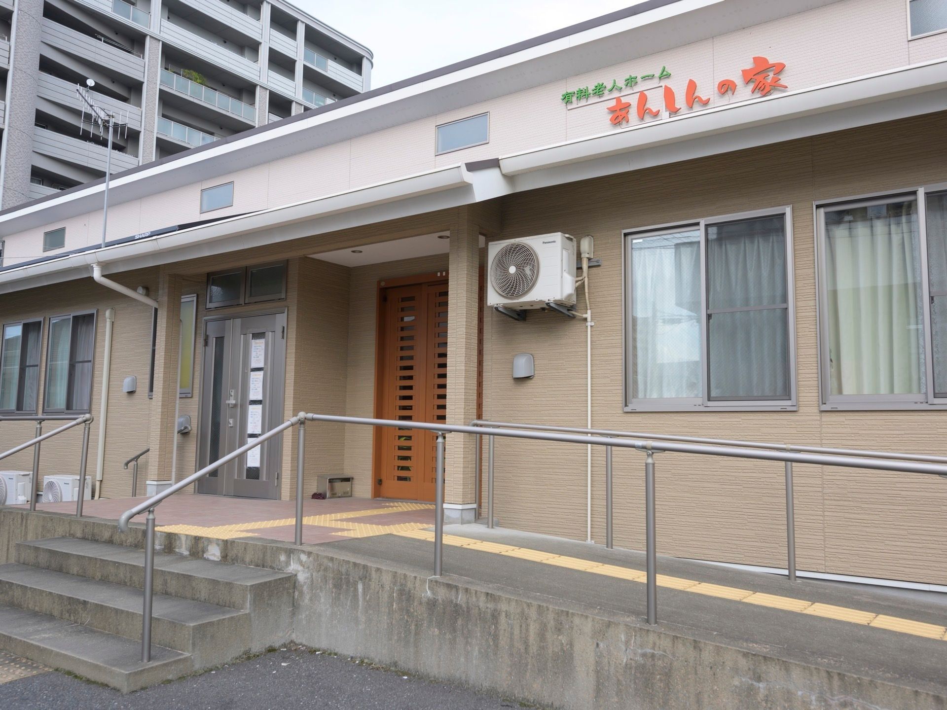 玄関には手すり付きのスロープが付いた平屋建ての建物。