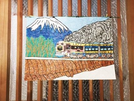 共有スペースのすりガラスに貼られた貼り絵のような作品。煙を吐く汽車の後ろには富士山がある。
