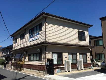 薄いベージュの外壁の2階建ての建物。アットホームな雰囲気で外壁には事業所名が書かれている。