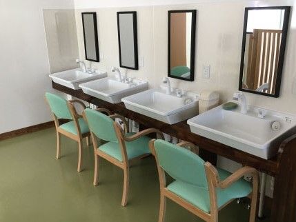 大きな洗面ボールが付いた洗面所が４つ並んでいる。それぞれに椅子がセットされ、鏡も付いている。
