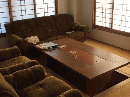 障子が設置された窓が付いた部屋には掘りごたつ風のテーブルがあり、ソファが置かれている。