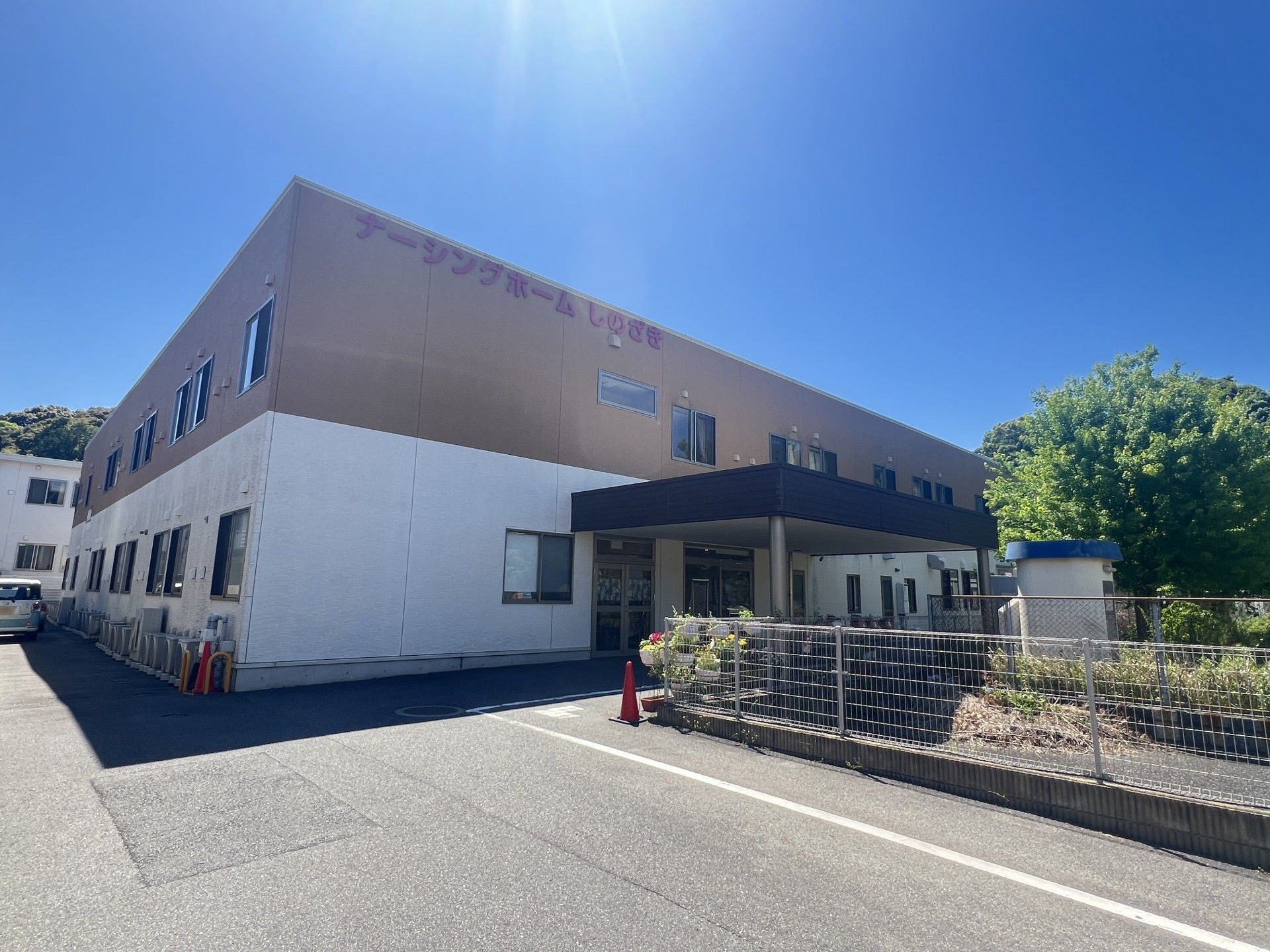 最上階に「ナーシングホームしのざき」と書かれている、白と薄茶の外壁の2階建て有料老人ホーム