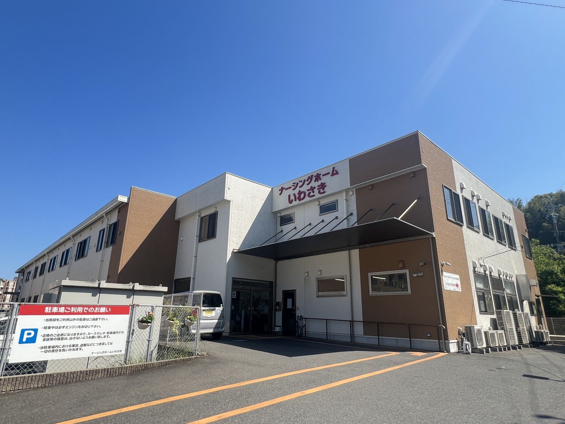 最上階に「ナーシングホームいわさき」と書かれている、白と薄茶の外壁の2階建て有料老人ホーム