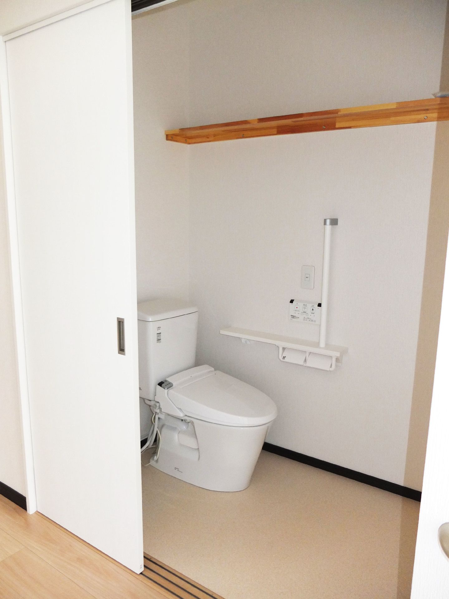 引き戸のトイレは手すりが付き、温水パネルも壁に付いている。