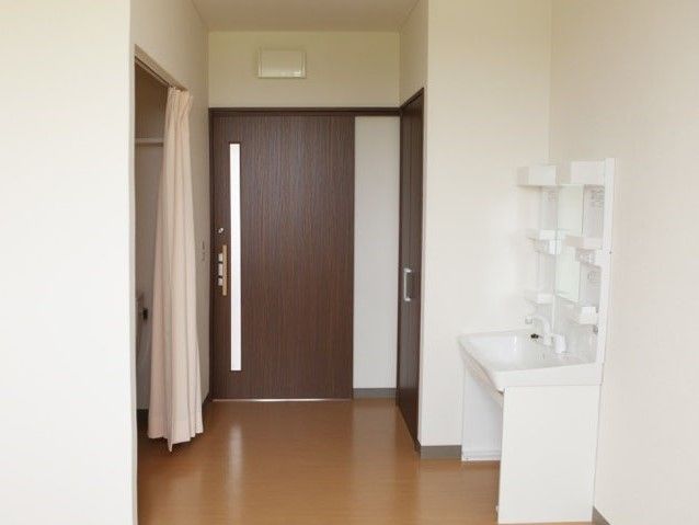 施設内の居室に洗面台がある様子。引き戸の入り口と左側にトイレがある様子
