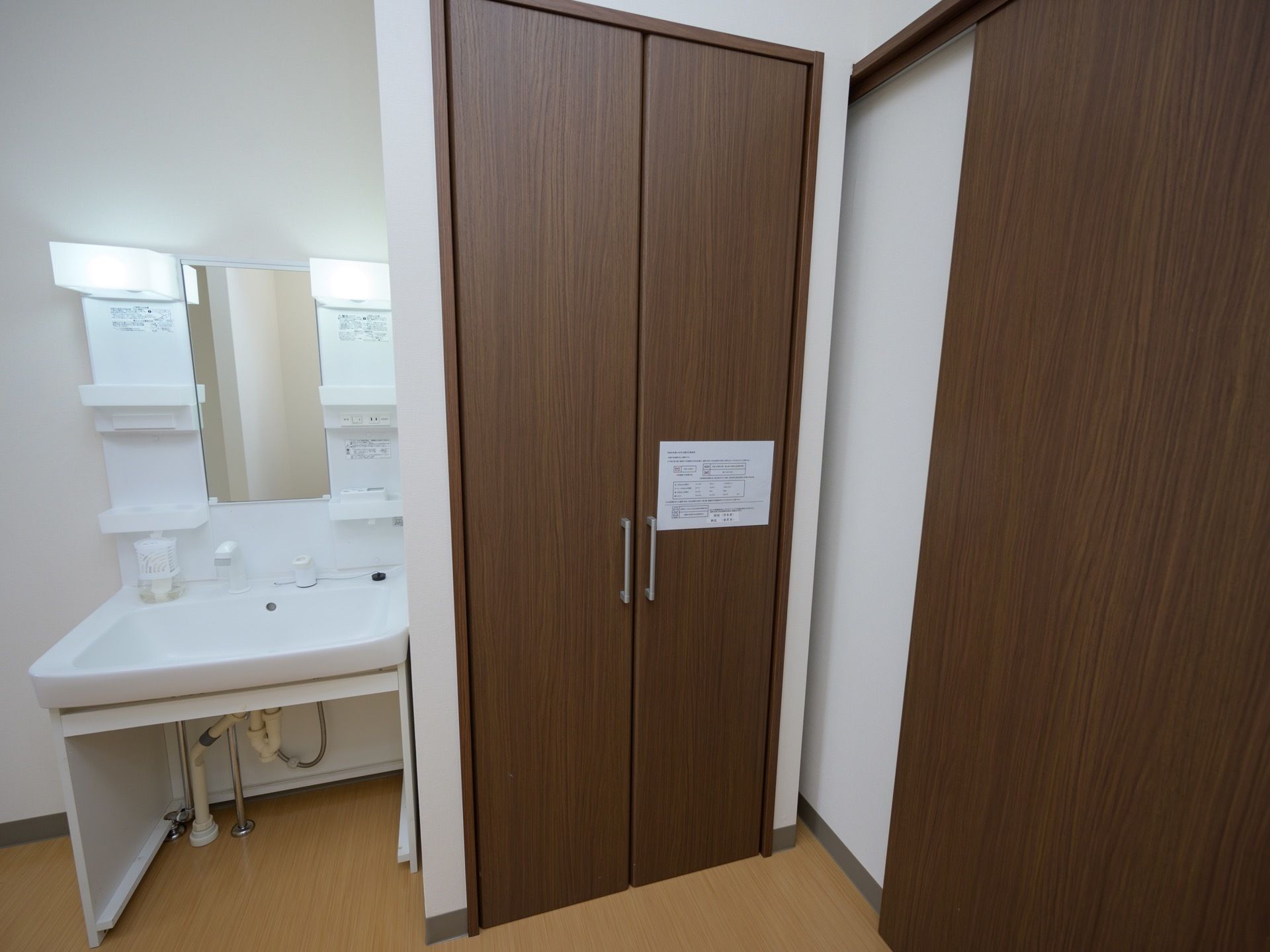 居室に設置された洗面台である。洗面器の下は広い空間が取られている。ミラー横には専用の照明と収納棚が付いている。
